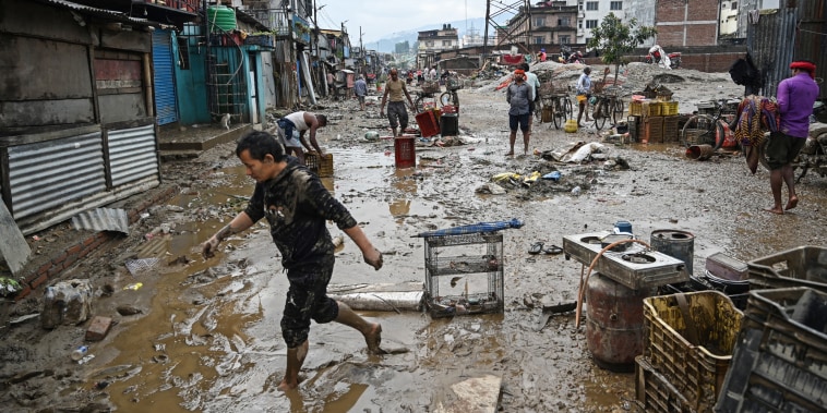 People walk through muddy streets filled with debris