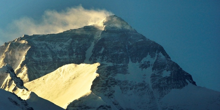 Wind blows snow off the summit at sunrise of the world's highest mountain Mount Everest, also known as Qomolangma, in the Tibet Autonomous Region