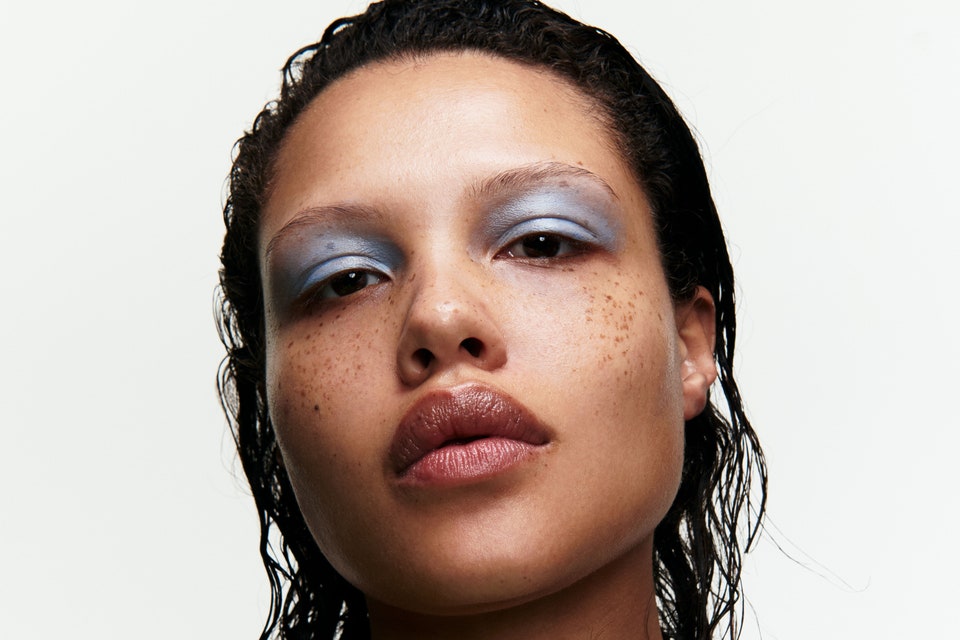 Model posing with blue eyeshadow and green shirt