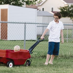 Boy pulling his nephew in a wagon in the family backyard