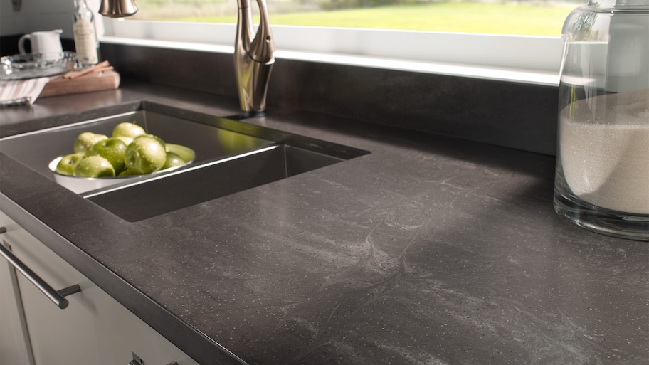 Dark Corian kitchen counter around sink and washed apples