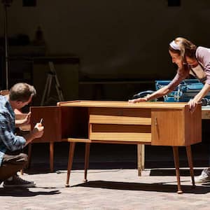 Couple refinishing furniture outside house