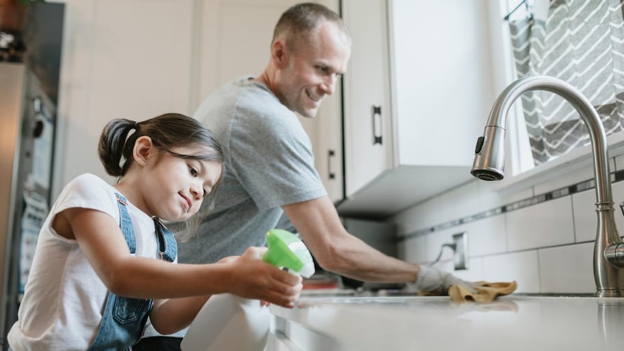 A father and his daughter cleaning their kitchen sink