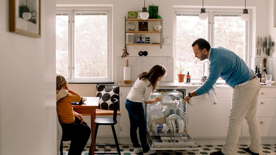 Father and daughter arranging utensils in dishwasher