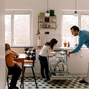 Father and daughter arranging utensils in dishwasher