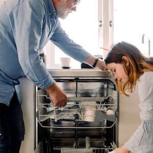 Grandfather and granddaughter cleaning dishwasher  