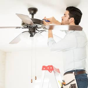 A handyman installing a ceiling fan