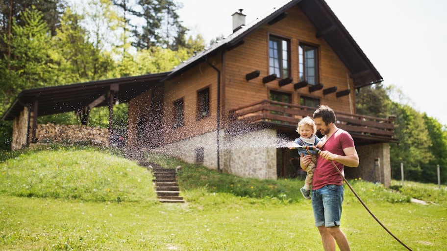 A little boy with his father watering the lawn