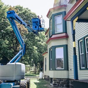 A man on cherry picker performing home maintenance