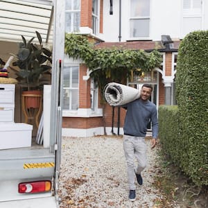 Man carrying rug moving out of house