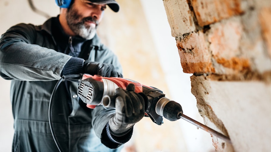 Professional knocking down a wall by using a drill