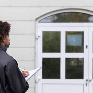 Man filling document in front of house