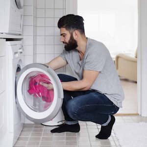 Man loading clothes in washing machine 