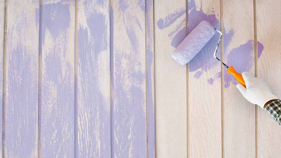 Man painting wooden wall