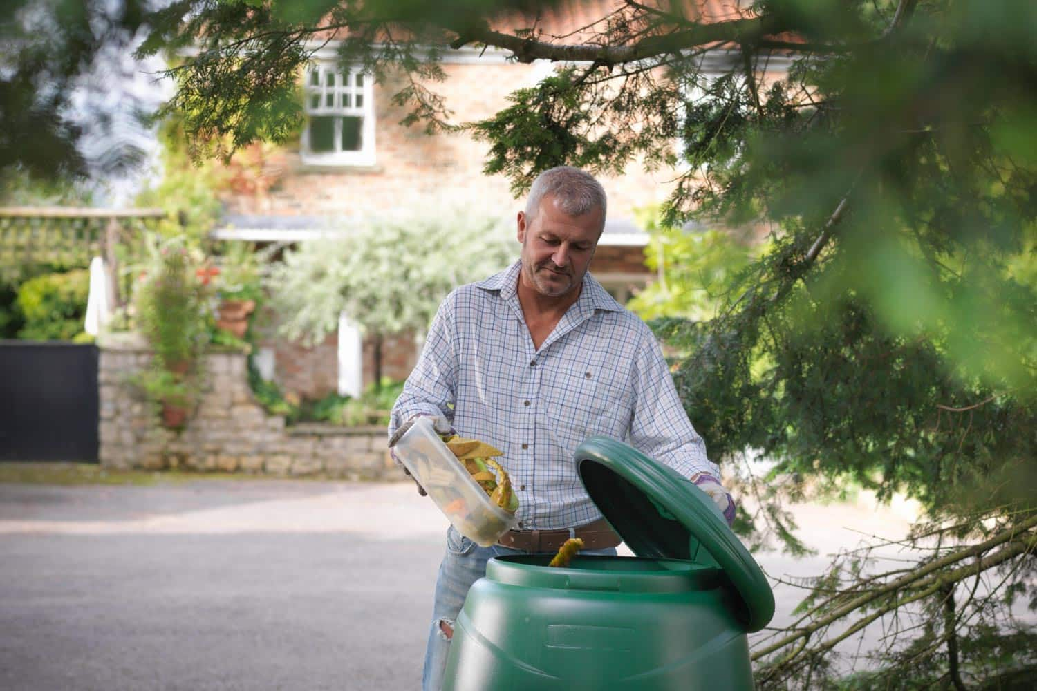 Man putting kitchen waste into compost bin