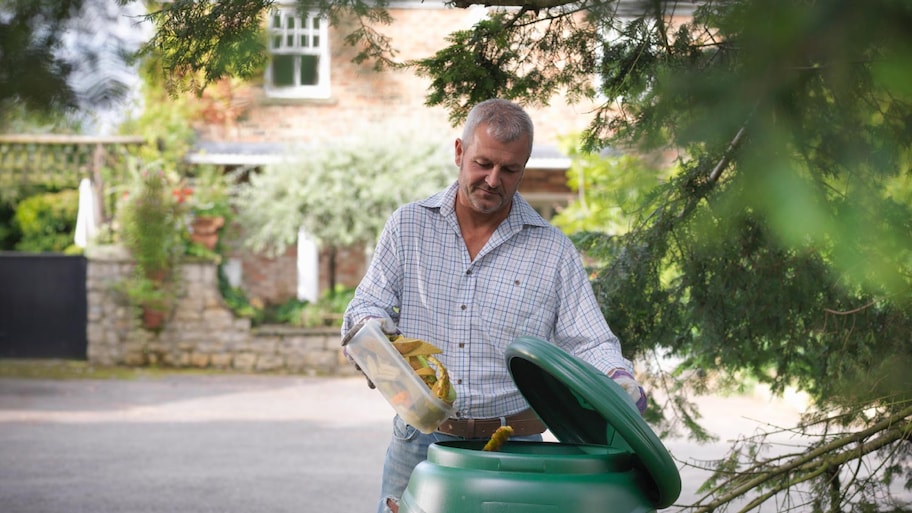 Man putting kitchen waste into compost bin