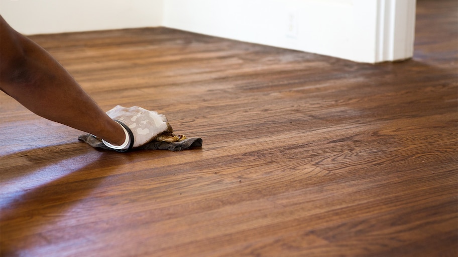 Person refinishing hardwood floors of home