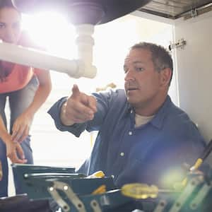 Plumber explaining pipe repair to homeowner