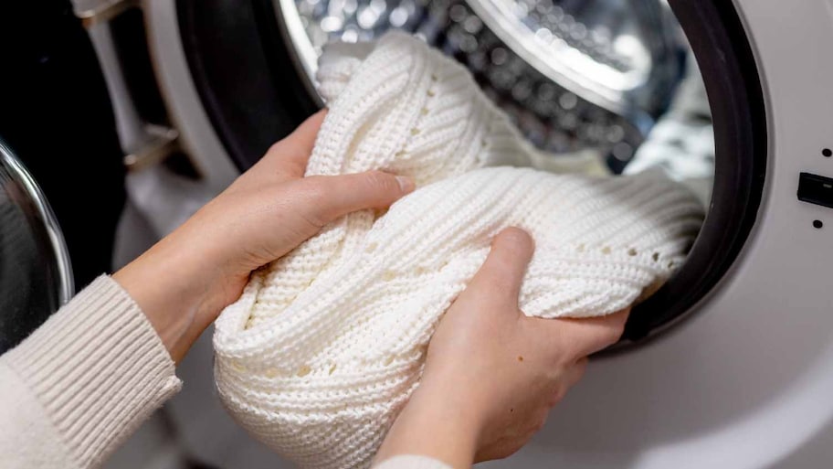 Woman putting sweater into the washing machine