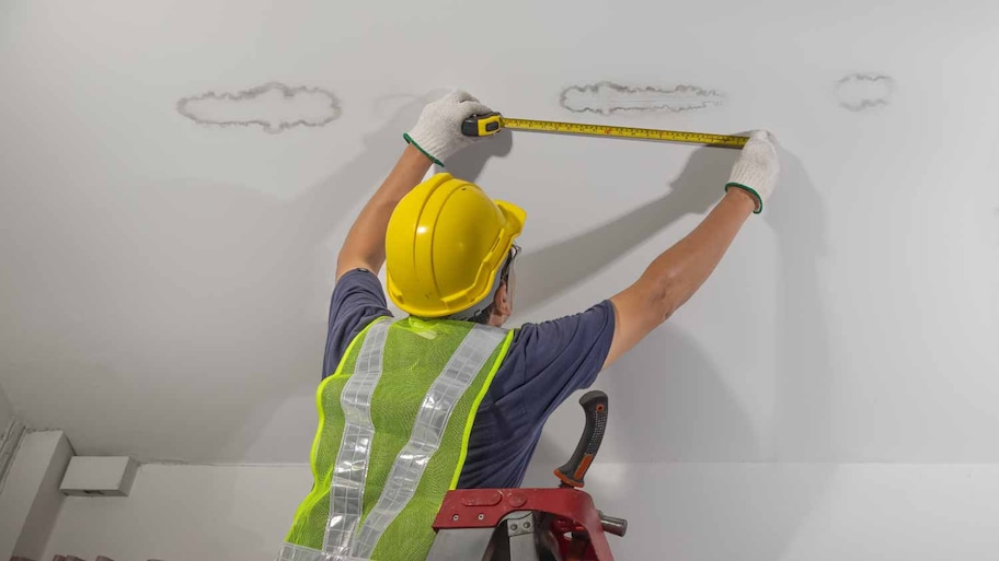 Worker fixing pipe in ceiling