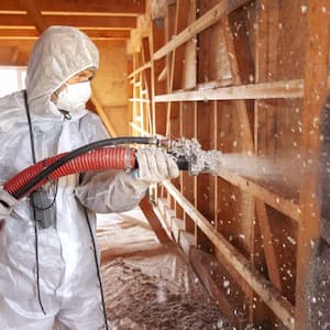 Worker spraying cellulose insulation
