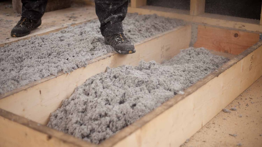 Worker walking next to cellulose insulation