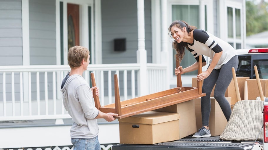 A young couple moving furniture into new home