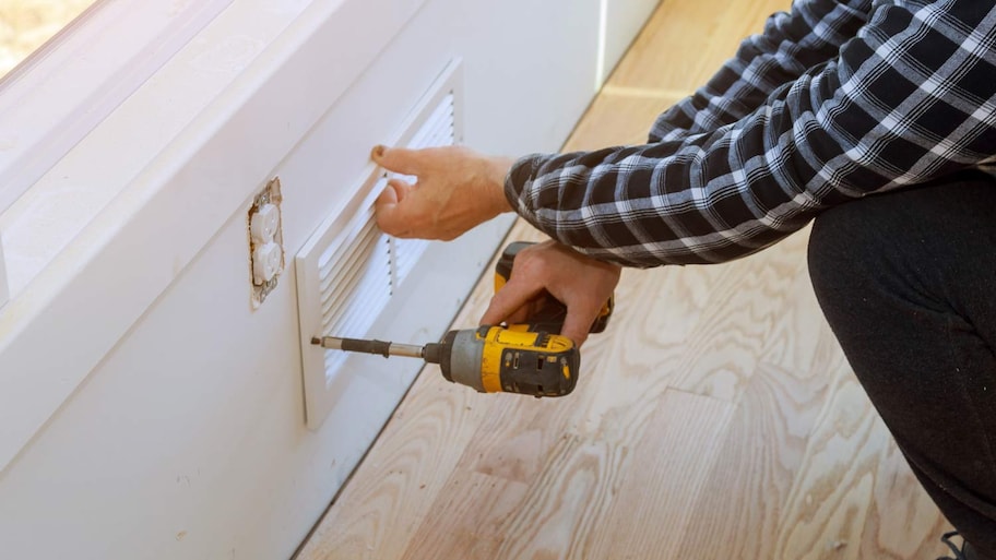 man screwing in air vent cover