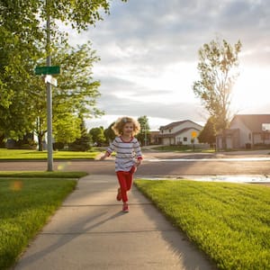 A little girl running down a sidewalk