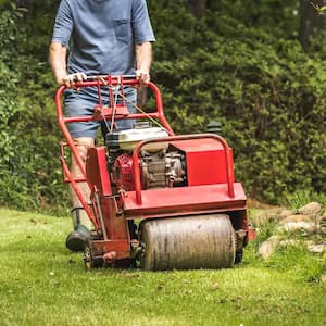 man using an aerator machine on grass