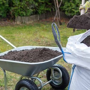 person pouring soil into wheelbarrow 