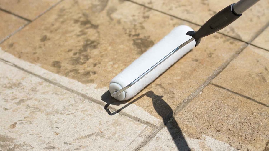 Using roller to apply sealant to a concrete driveway