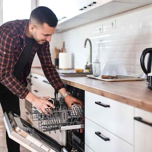 Man arranging dishes in the dishwasher at home
