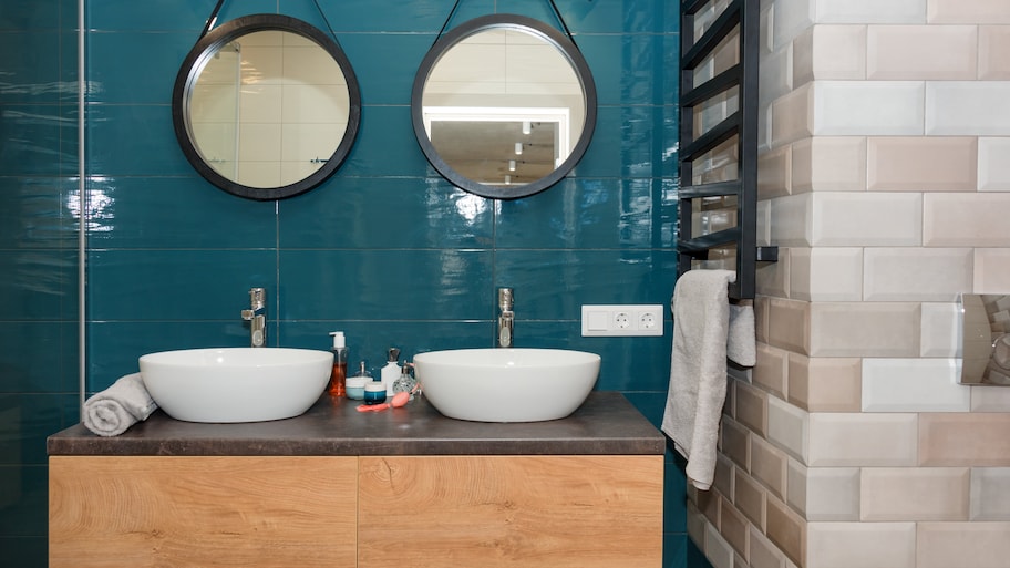 Modern bathroom with two round mirrors, two white vessel sinks, and a floating wooden vanity