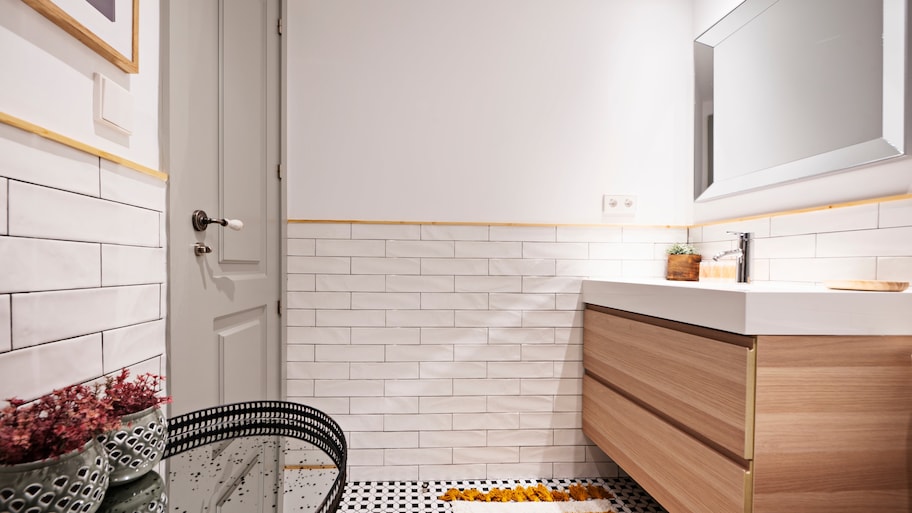 Small bathroom with subway tile backsplash, wooden vanity, and beveled mirror