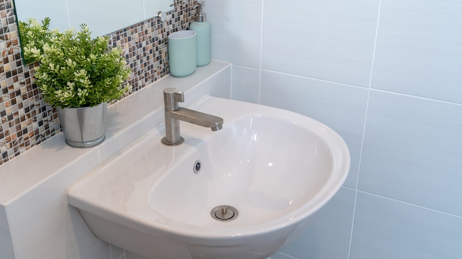 Small bathroom with white tile walls and a glass tile backsplash