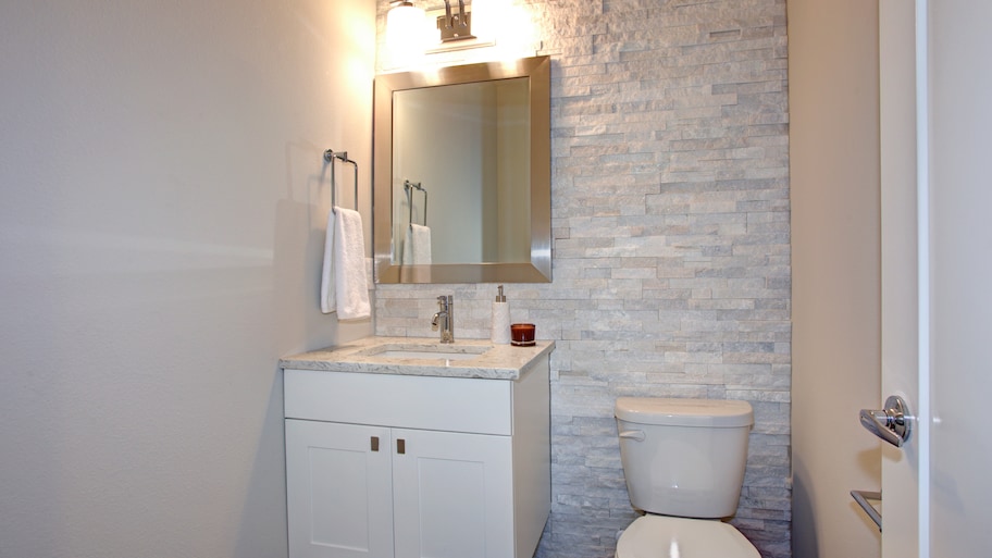 Small bathroom with stacked textured tile, a floating vanity, and a rectangular silver mirror