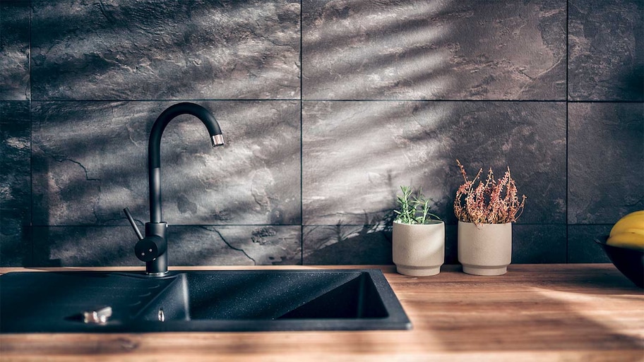 A black tile kitchen backsplash