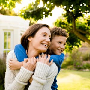 A boy embracing mother outside house