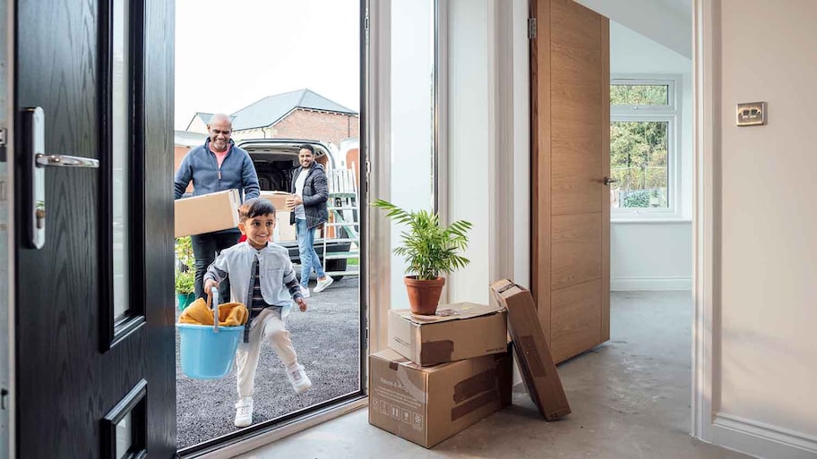 Family carrying boxes moving into a new home