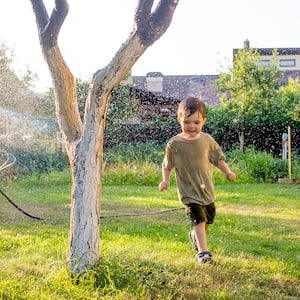 little boy running around in the sprinklers  