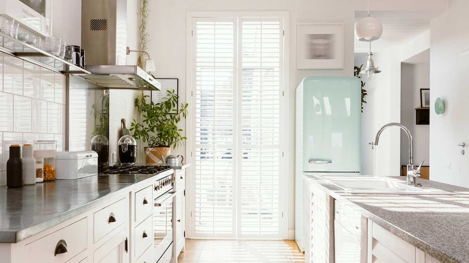 A bright white kitchen with a pastel fridge