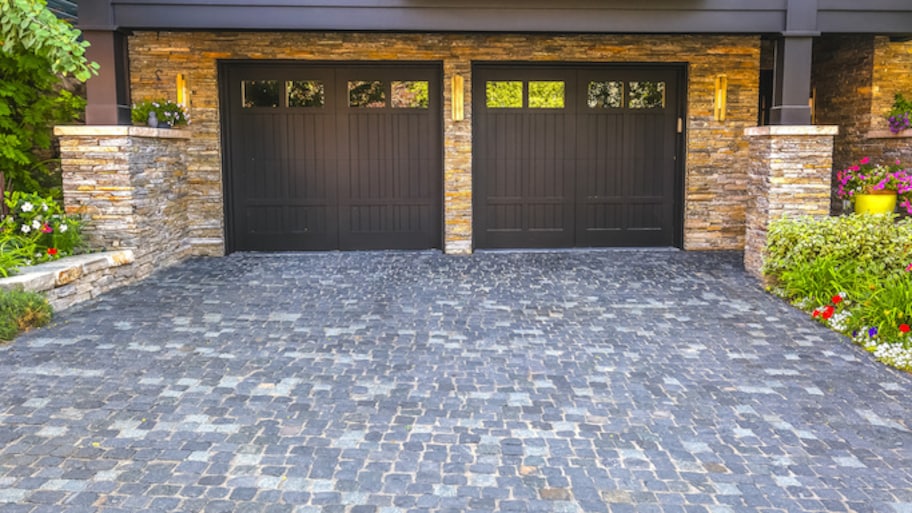 brown double garage doors and stone paved driveway