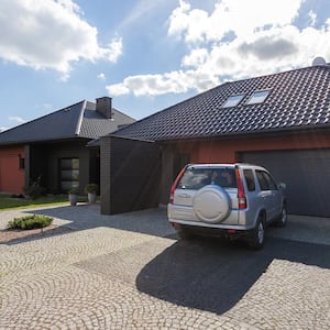 A car parked in the driveway in front of a garage door