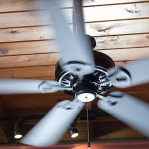 A ceiling fan shows motion blur as its blades spin around.