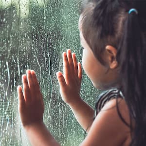 Child looking at the rain through a window