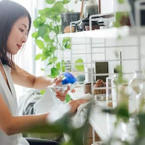 Woman at home cleaning shelves with cleaning spray