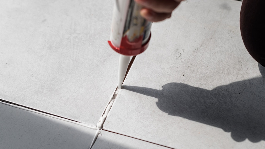 Close-up of a man applying grout between ceramic tiles