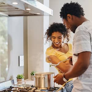 Couple cooks meal in a pan on a gas stove