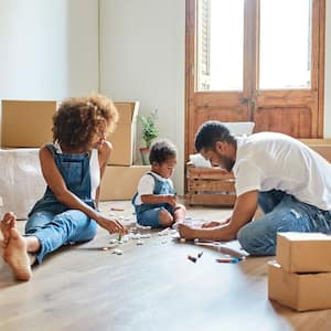 A couple with their baby opening moving boxes on the floor